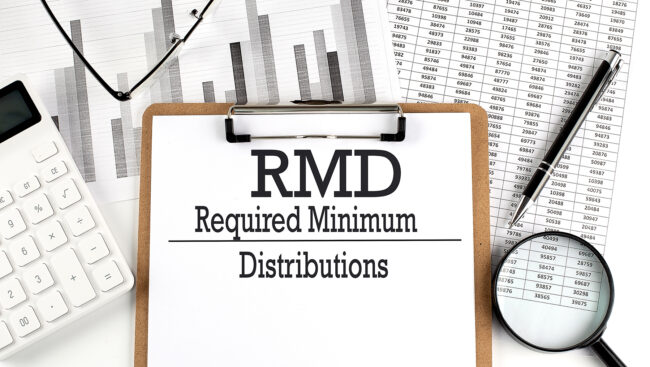 Paper with RMD Required Minimum Distributions on a chart with calculator,pen and magnifier